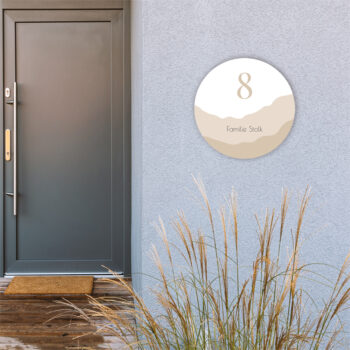 Naambord Mountains op een beton gestucte muur, dit huisnummerbord is wit met beige tinten